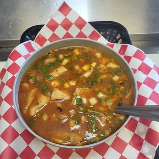 Bowl of menudo topped with onion and cilantro